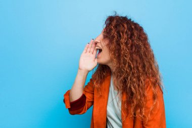 Genç, kızıl saçlı, zarif bir kadın bağırıyor ve avuç içiyle ağzını açıyor..