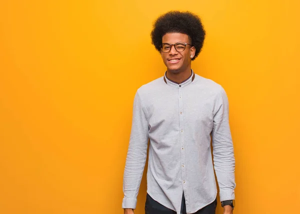 年轻的非洲裔美国男子越过橙色的墙壁眨眼 友善和无忧无虑的手势 — 图库照片