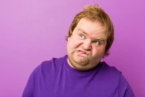 Young authentic redhead fat man frowning face in displeasure, keeps arms folded.