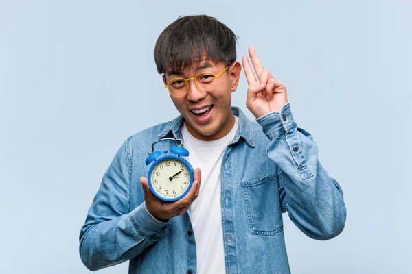 Mladý Číňan Drží Budík Zábavný Šťastný Dělá Gesto Vítězství — Stock fotografie