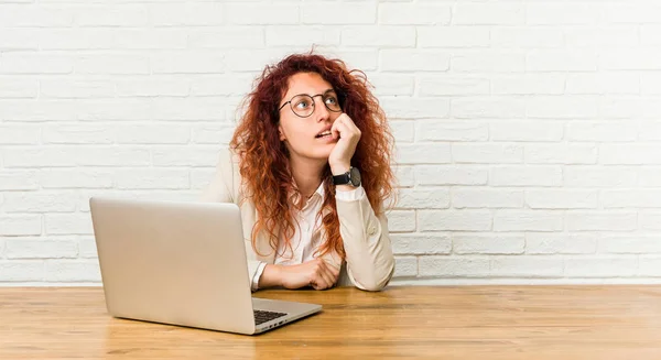 Joven Pelirroja Rizada Mujer Trabajando Con Portátil Relajado Pensando Algo — Foto de Stock