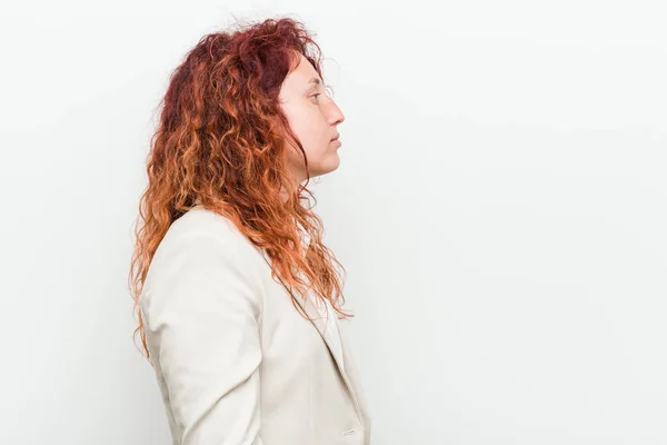 Young natural redhead business woman isolated against white background gazing left, sideways pose.