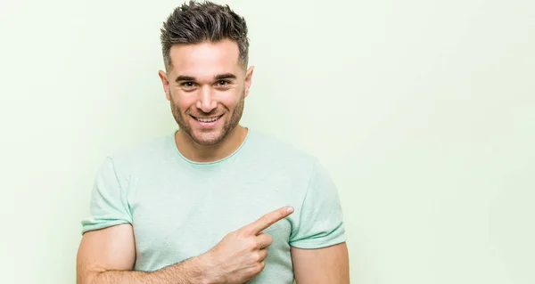 Young Handsome Man Green Background Smiling Pointing Aside Showing Something — Stock fotografie