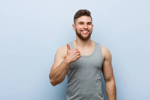 Young handsome fitness man smiling and raising thumb up