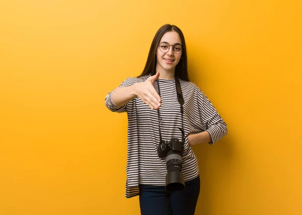 Young photographer woman reaching out to greet someone
