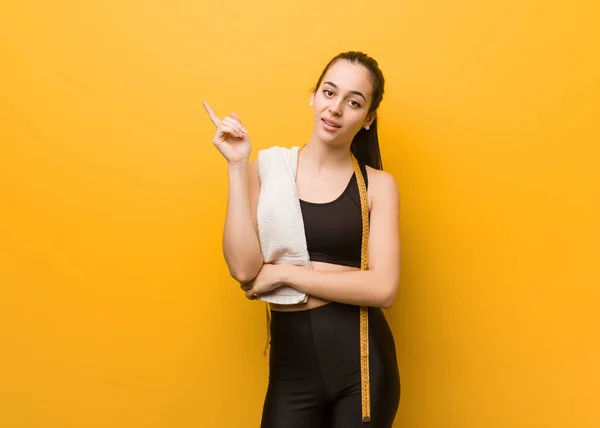 Young fitness girl pointing to the side with finger