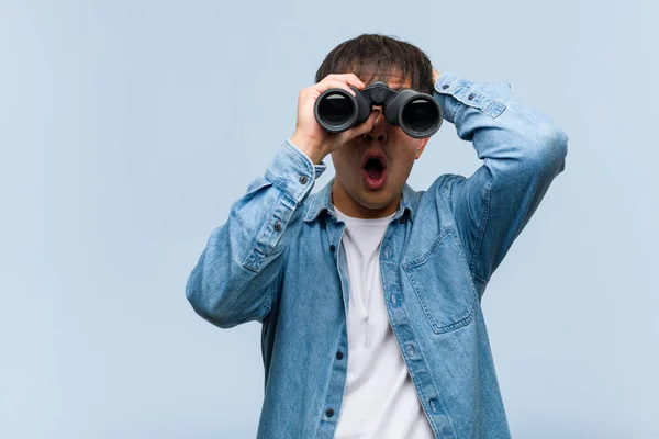 Young Chinese Man Holding Binoculars Worried Overwhelmed — Stock Photo, Image