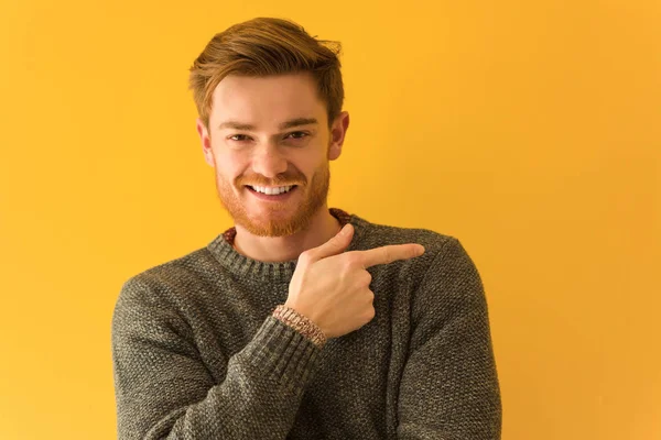 Young redhead man face closeup smiling and pointing to the side