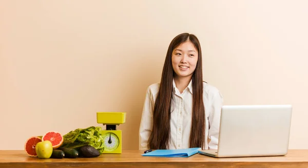 Young nutritionist chinese woman working with her laptop dreaming of achieving goals and purposes