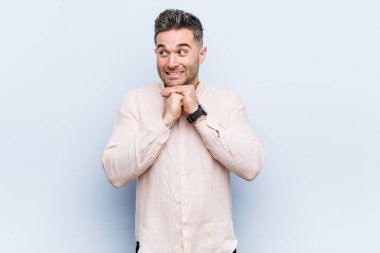 Yakışıklı yakışıklı adam ellerini çenesinin altında tutuyor, mutlu bir şekilde yan tarafa bakıyor..