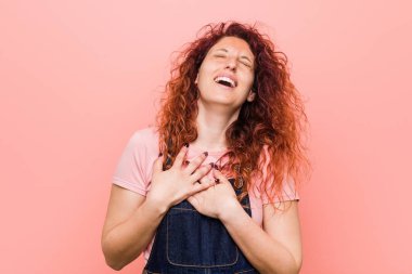 Kot pantolon giyen kızıl saçlı, genç ve güzel bir kadın. Gülüyor, elini kalbe koyuyor, mutluluk kavramını koruyor..