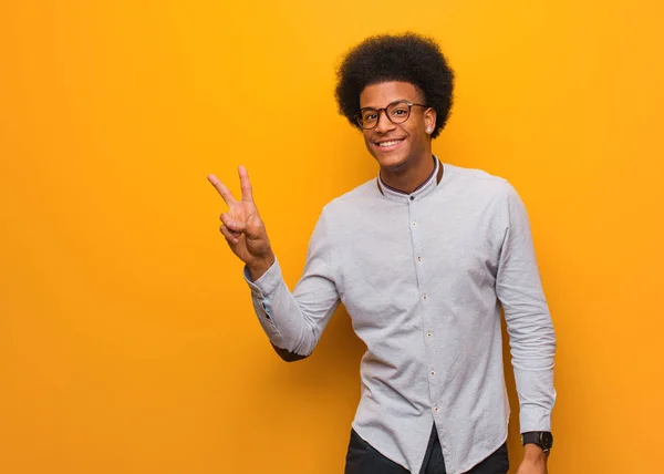 年轻的非洲裔美国人在橙色墙做一个胜利的姿态 — 图库照片