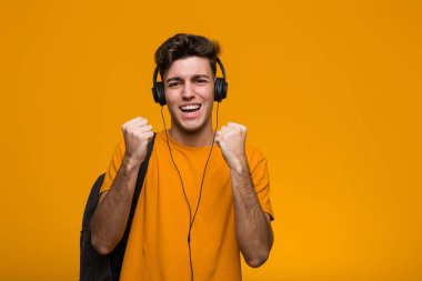 Genç havalı öğrenci kulaklıkla müzik dinliyor zaferi veya başarıyı kutluyor.