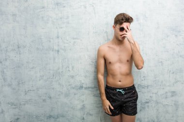 Mayo giyen genç beyaz adam kameraya parmaklarıyla göz kırpıyor, yüzünü kapatmaktan utanıyor..