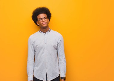 Turuncu bir duvarın ardında bir fikir düşünen Afrikalı genç bir Amerikalı.