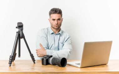 Genç yakışıklı fotoğrafçılık öğretmeni hoşnutsuzca surat asıyor, kollarını kavuşturuyor..