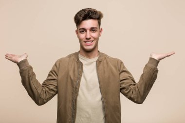 Kahverengi ceket giyen genç beyaz adam kollarıyla terazi yapıyor, mutlu ve kendinden emin hissediyor..