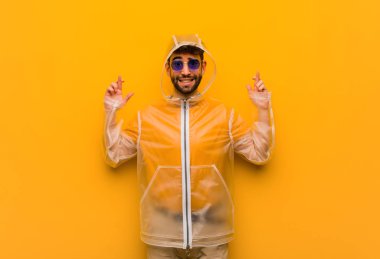 Yağmurluk giyen genç adam şans diliyor.