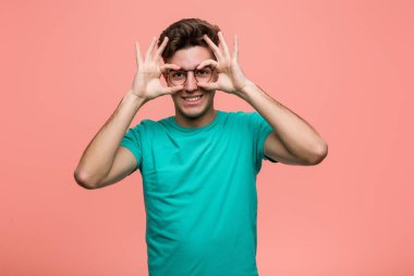 Genç, havalı, beyaz bir adam. Gözlerinin üzerinde işaret var.