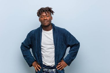 Genç Afrikalı, pijama giyen, kendinden emin bir zenci ellerini kalçasından ayırmıyor..