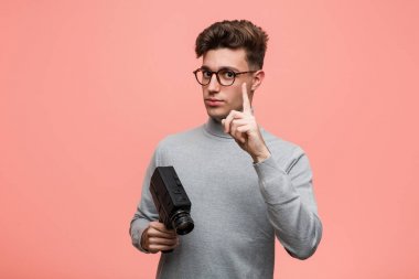 Genç entellektüel bir adam bir numaralı kamerayı parmağıyla gösteriyor..