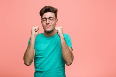 Kafkasyalı genç adam yumruğunu kaldırıyor, mutlu ve başarılı hissediyor. Zafer konsepti.