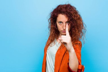 Genç, kızıl saçlı, zarif bir kadın bir numarayı parmağıyla gösteriyor..