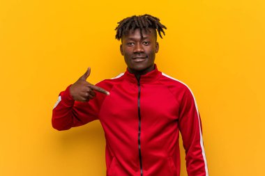 Genç fitness Afrikalı bir adam gömlek fotokopi odasını elle gösteriyor, gururlu ve kendinden emin.