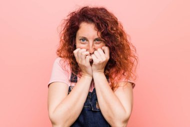 Kot pantolon giyen kızıl saçlı, genç ve güzel bir kadın. Bir şeye gülüyor, elleriyle ağzını kapatıyor..