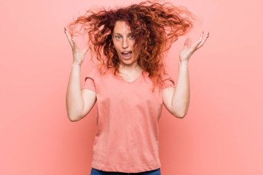 Genç doğal ve otantik kızıl saçlı kadın zaferi ya da başarıyı kutluyor, şaşırıyor ve şok oluyor..