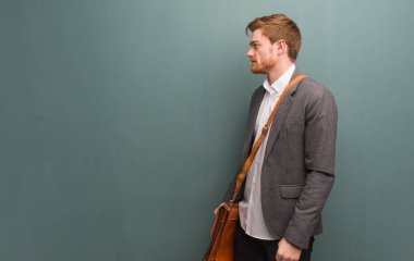 Genç kızıl saçlı iş adamı ön tarafa bakıyor.