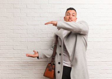 Genç Latin iş adamı elinde çok şaşırmış ve şok olmuş bir şey tutuyor.