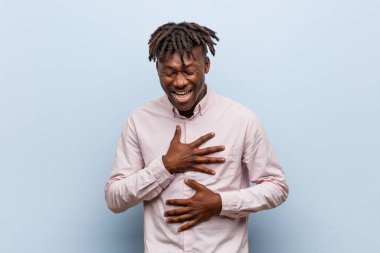 Genç iş adamı Afrikalı siyah adam mutlu bir şekilde gülüyor ve ellerini karnının üstünde tutarak eğleniyor..