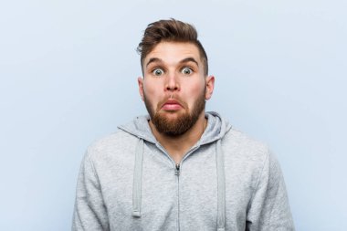 Genç yakışıklı jimnastikçi omuz silker ve gözleri açık kalır..