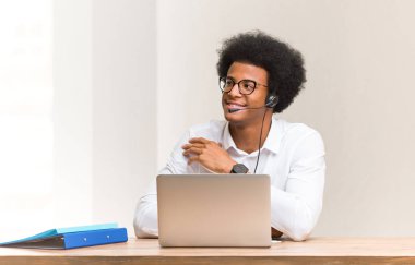 Genç pazarlamacı, gülümseyen, kendine güvenen ve kollarını kavuşturan siyahi bir adam.