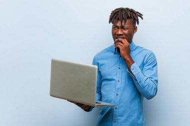 Genç Rasta siyah adam dizüstü bilgisayar tutuyor tırnaklarını yiyor, gergin ve çok endişeli..