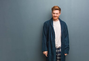 Pijamalı genç kızıl adam göz kırpıyor, komik, dost canlısı ve kaygısız.