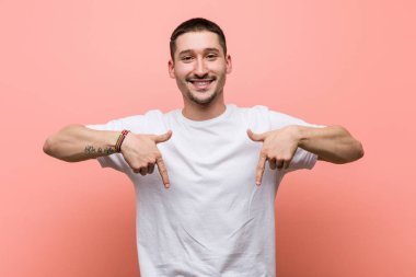 Genç sıradan bir adam parmaklarıyla aşağıya doğru işaret ediyor, pozitif duygu..