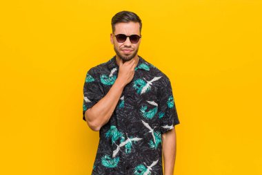 Filipinli genç adam yazlık giysiler giyiyor. Virüs ya da enfeksiyon yüzünden boğazında ağrı var..