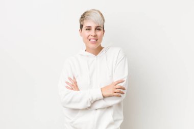 Kendine güveni olan beyaz kapüşonlu bir kadın, kararlılıkla kollarını kavuşturuyor..