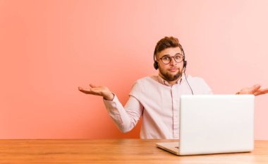 Çağrı merkezinde çalışan genç bir adam şüpheyle hareket ederken omuzlarını silkiyor..