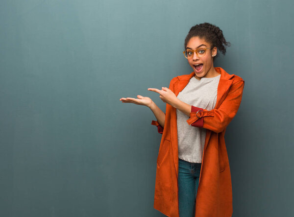 Young black african american girl with blue eyes holding something with hand