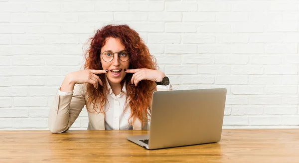 Jovem Ruiva Encaracolado Mulher Trabalhando Com Seu Laptop Sorri Apontando — Fotografia de Stock