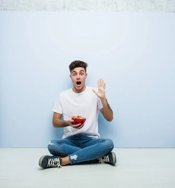 Ung Man Äter Spannmål Sittandes Golvet Firar Seger Eller Framgång — Stockfoto