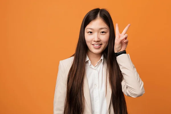 Young business chinese woman showing victory sign and smiling broadly.