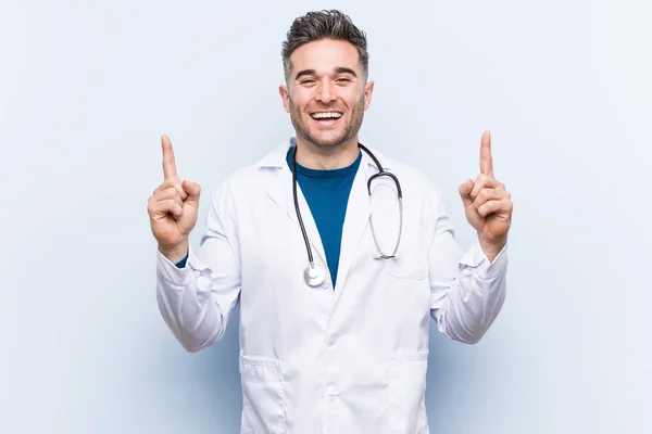 Junger Hübscher Arzt Zeigt Mit Beiden Vorderen Fingern Nach Oben — Stockfoto