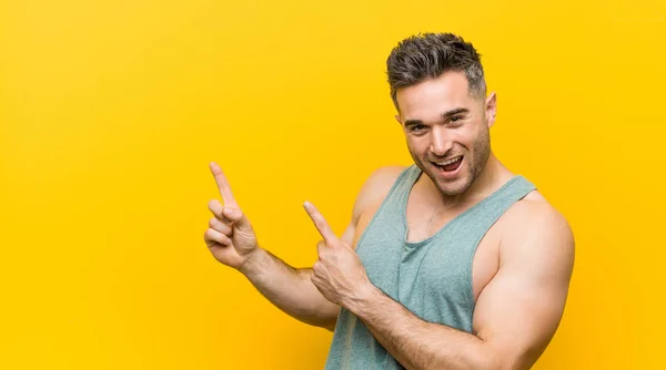 Genç Fitness Adamı Sarı Arka Planda Işaret Parmağıyla Fotokopi Alanını — Stok fotoğraf