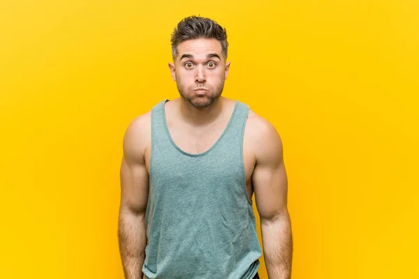 Mladý Fitness Muž Žlutém Pozadí Fouká Tváří Unavený Výraz Koncept — Stock fotografie