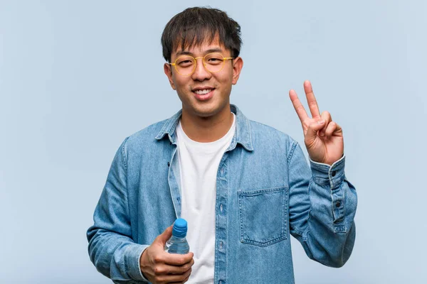 Ung Kinesisk Man Som Håller Vattenflaska Som Visar Nummer Två — Stockfoto
