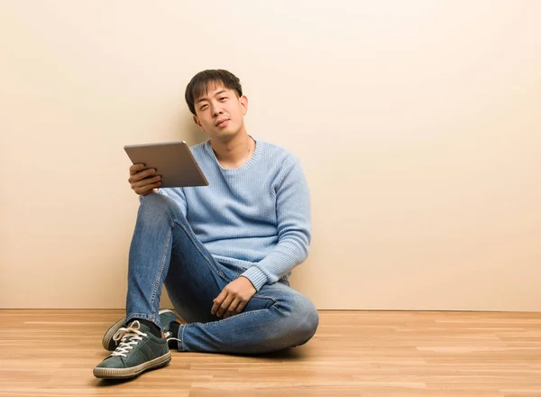 Jovem Chinês Sentado Usando Seu Tablet Com Mãos Nos Quadris — Fotografia de Stock